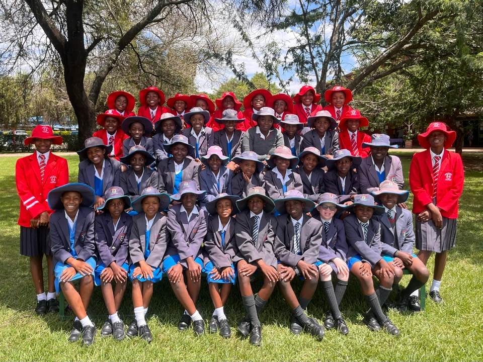 Formal cohort portrait under the trees in red and grey blazers